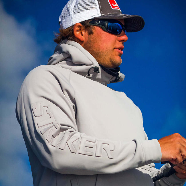 Man wearing a gray hoodie with 'Striker' branding against a blue sky.