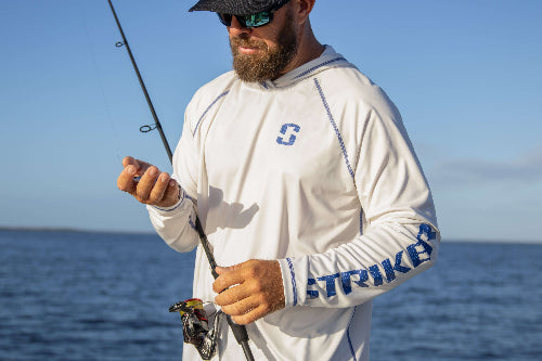 Man holding a fishing rod with a clear blue sky and ocean background