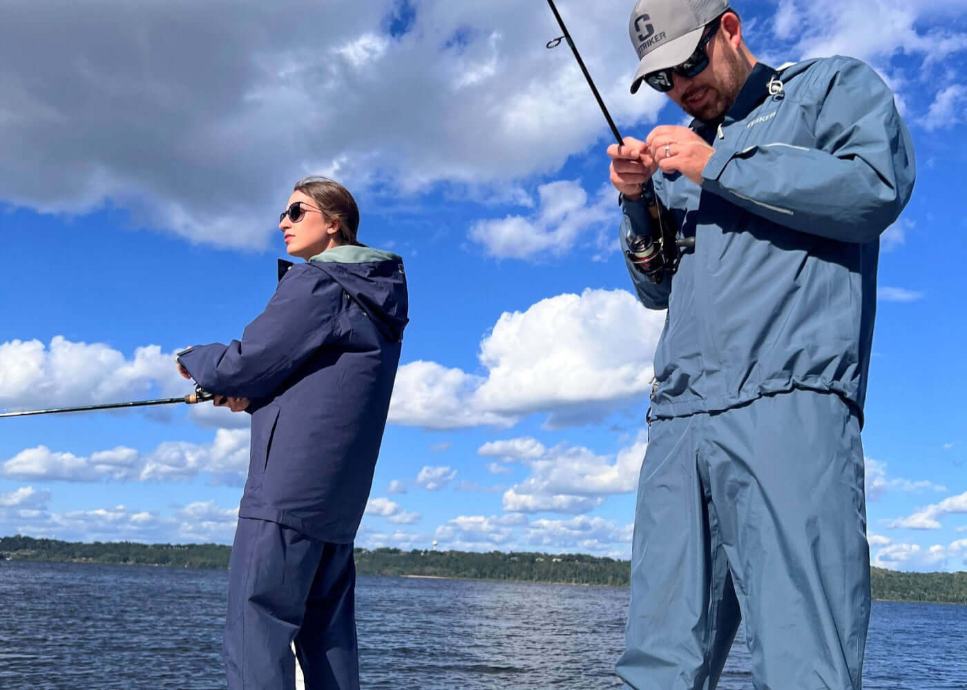 Two people fishing on a lake with a clear blue sky.
